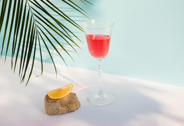 Summer composition with red beverage Lemon slice Stone podium and palm leaf Summer drink concept