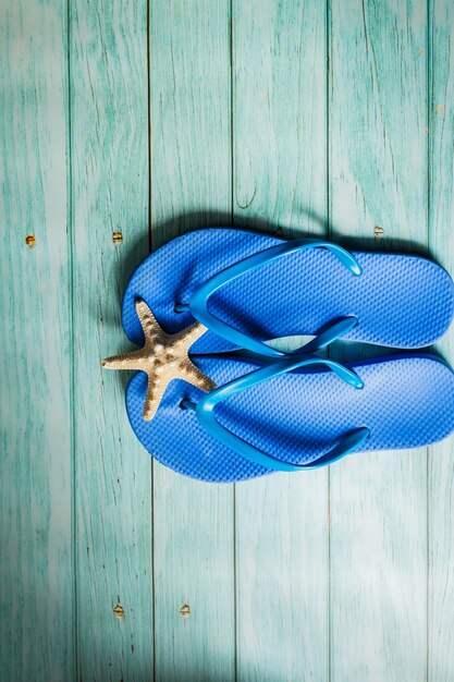 Summer concept -  blue beach slippers on blue wooden floor. Top view