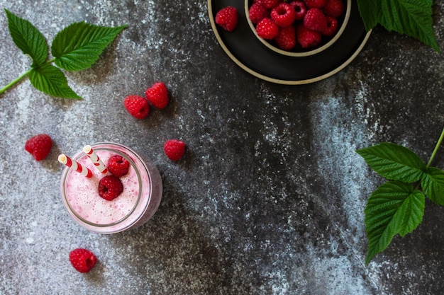 Summer cool milkshake Raspberry protein shake in glass on a dark background Top view