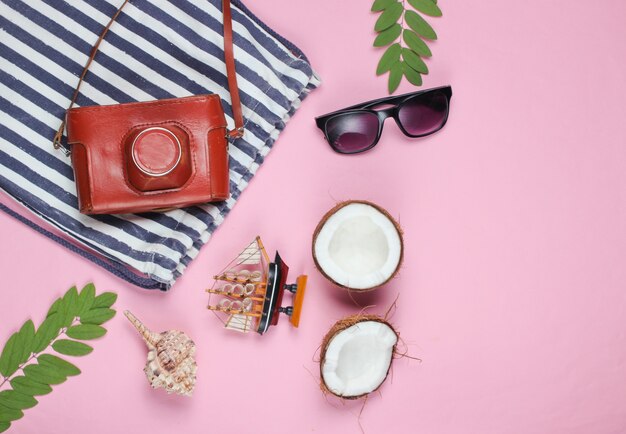 Summer creative background. Beach striped bag, accessories on a pink background. Top view.