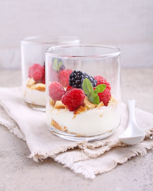 Summer dessert with berries cream and cookies in glasses