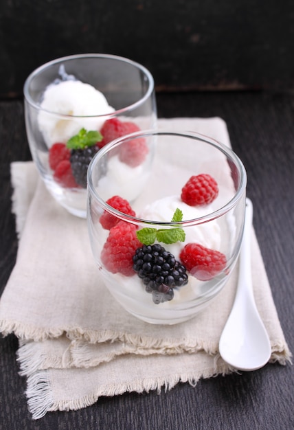 Summer dessert with berries and ice cream in glasses on a black background