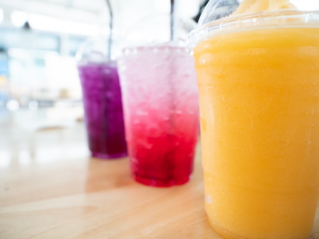 Summer drink in disposable plastic cup and dome cap of mango frappe, strawberry soda and blueberry