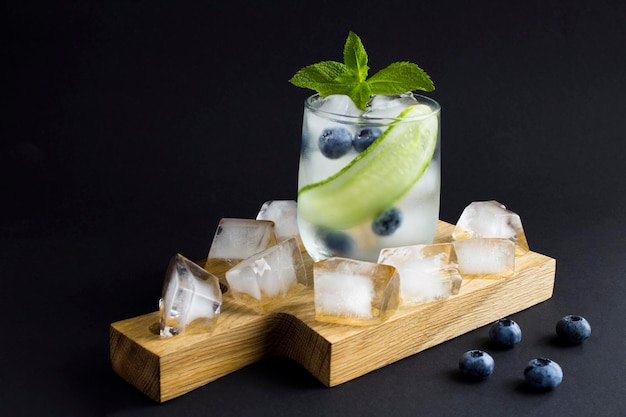 Summer drink with cucumber mint and blueberry in the drinking glass on the dark background Copy space