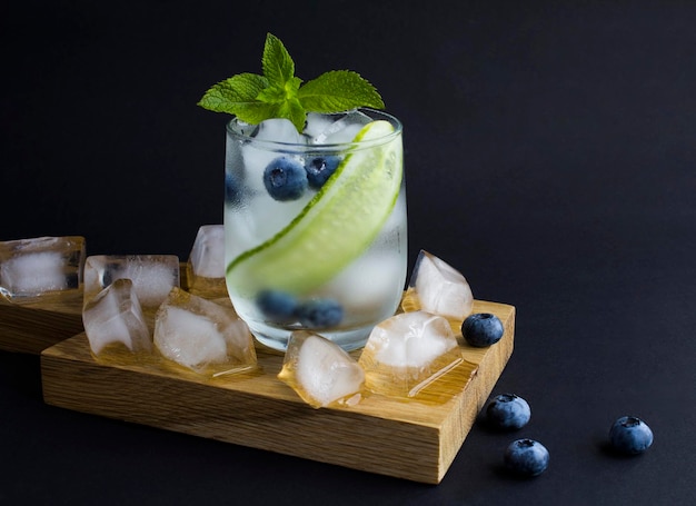 Summer drink with cucumber mint and blueberry in the glass on the dark background Copy space