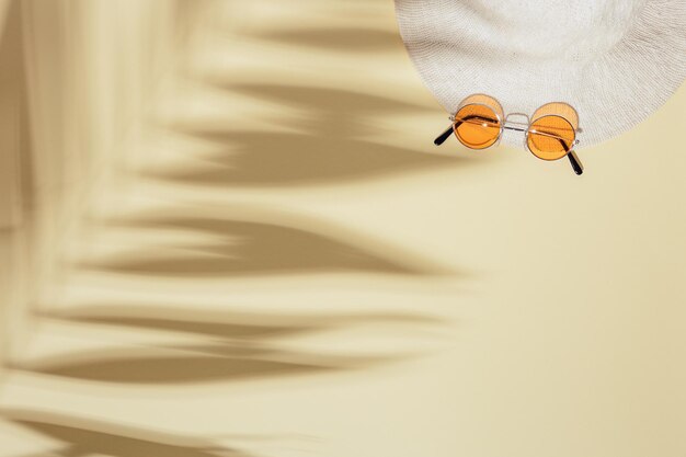 Summer flat lay with sun hat colored sunglasses on sandy color background Concept of summer hot day on beach