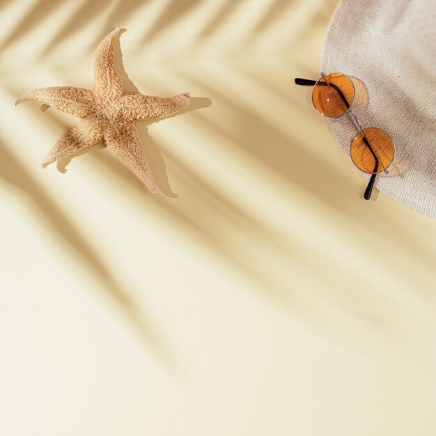 Photo summer flat lay with sun hat colored sunglasses starfish on sandy with shadows of palm leaves