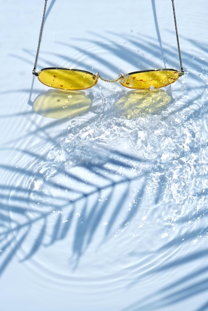 Summer flat lay with yellow sunglasses on water background