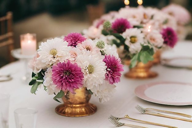 Summer floral bouquet with white and pink asters on table in golden vase at wedding