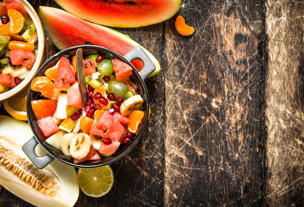 Summer food . Salad of tropical fruits. On wooden background.