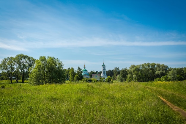 Summer green grass field and old white church, rural landscape.