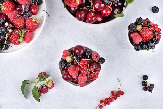 Summer harvest of strawberries, raspberries, sweet cherries, currants on a gray background, top view.