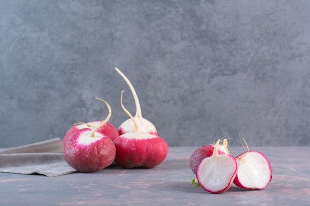 Summer harvested red fresh radishes on stone background.