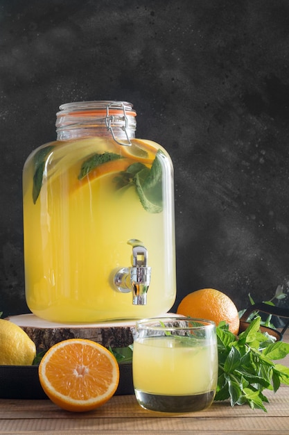 Summer healthy detox drink Lemonade with orange lemon and mint in mason jar on wooden board