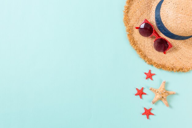 Summer holiday background with straw hat and seashells on blue background top view with copy space.