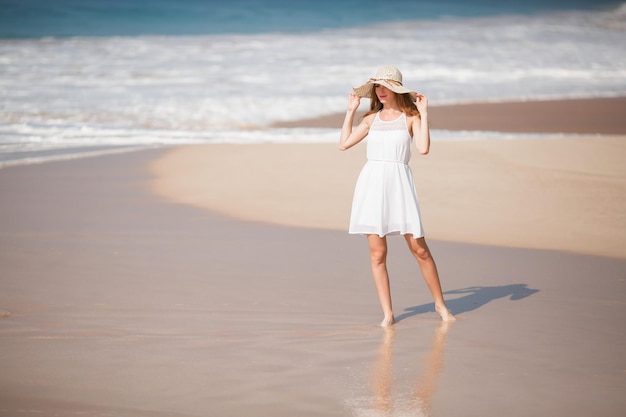 Summer holiday fashion concept tanning woman wearing sun hat at the beach on a white sand shot from above