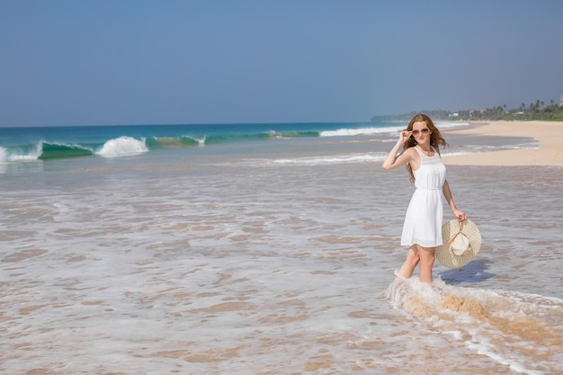 Summer holiday fashion concept tanning woman wearing sun hat at the beach on a white sand shot from above