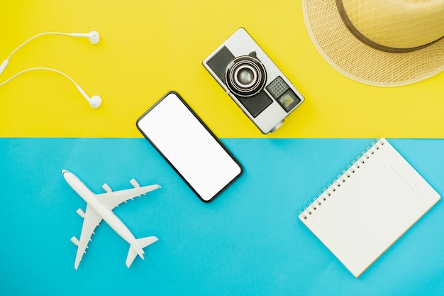 Summer holiday and travel concept. Top view of black smartphone and glasses with camera