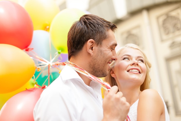 summer holidays, celebration and dating concept - happy couple with colorful balloons in the city