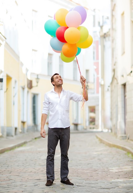 summer holidays, celebration and lifestyle concept - man with colorful balloons in the city