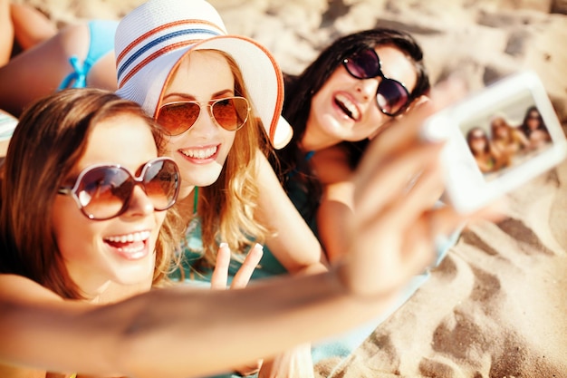 summer holidays, technology and beach concept - girls making self portrait on the beach