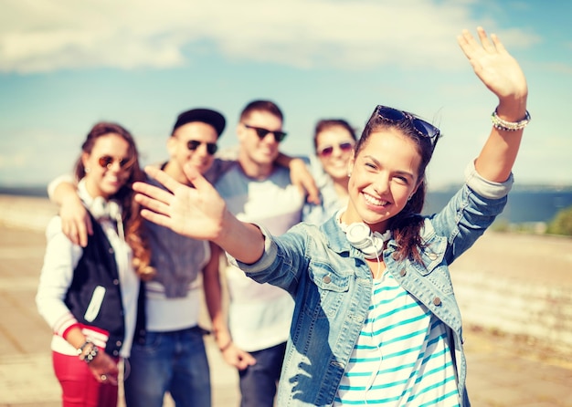 summer holidays and teenage concept - teenage girl in sunglasses and headphones hanging out with friends outside