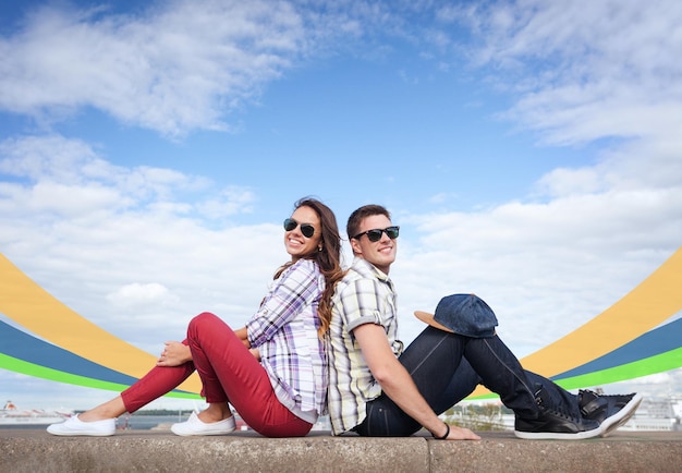 summer holidays and teenage concept - teenagers sitting back to back