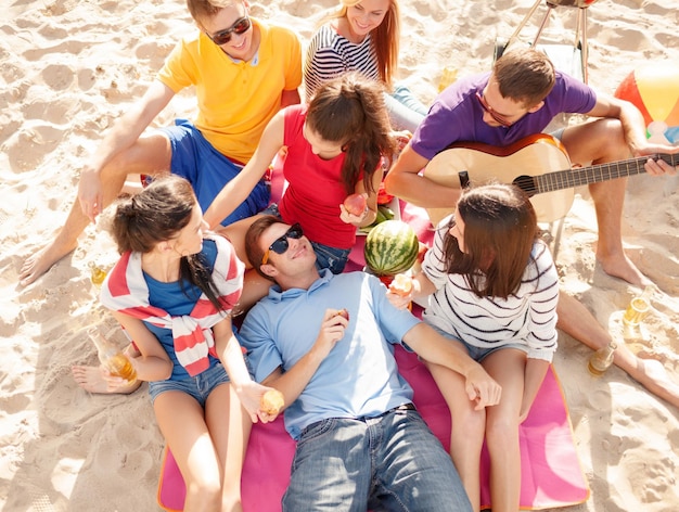 summer, holidays, vacation, music, happy people concept - group of friends with guitar having fun on the beach