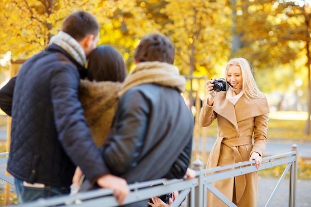 summer, holidays, vacation, travel, tourism, happy people concept - group of friends or couples having fun with photo camera in autumn park