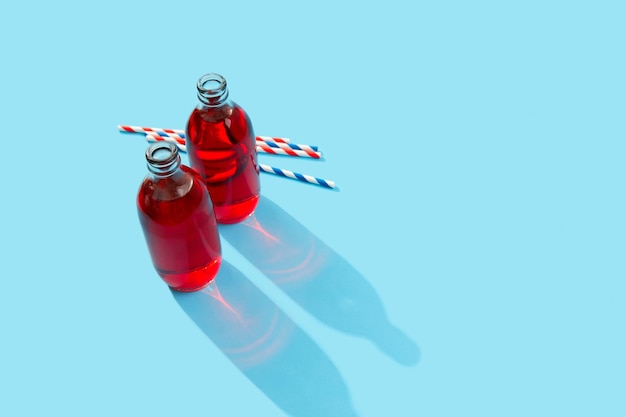 Summer iced cranberrie punch cocktail in bottle on blue background