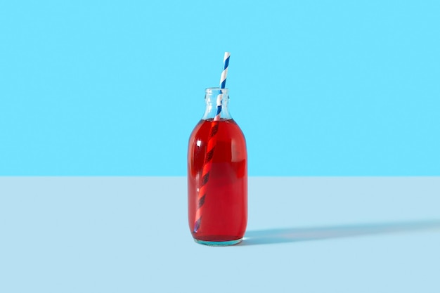 Summer iced cranberrie punch cocktail in bottle on blue background