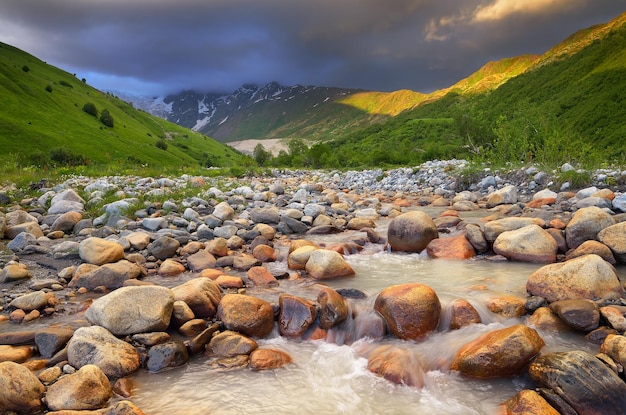 Summer landscape with the mountain river. Black clouds over a mountain valley. Zemo Svaneti, Georgia