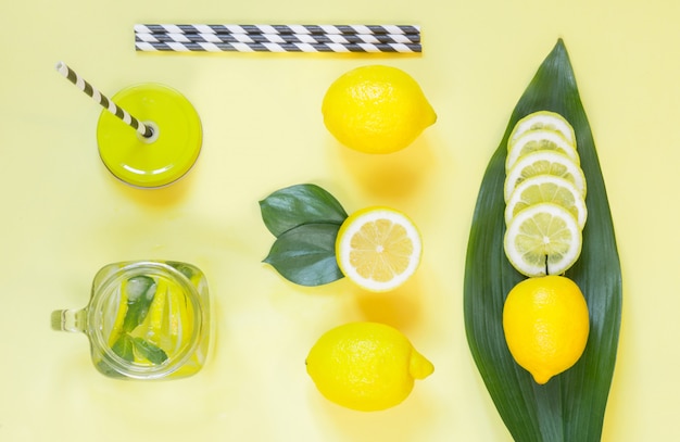 Summer lemon composition for cooking detox lemonade with mint and ice in mason jar on yellow. 