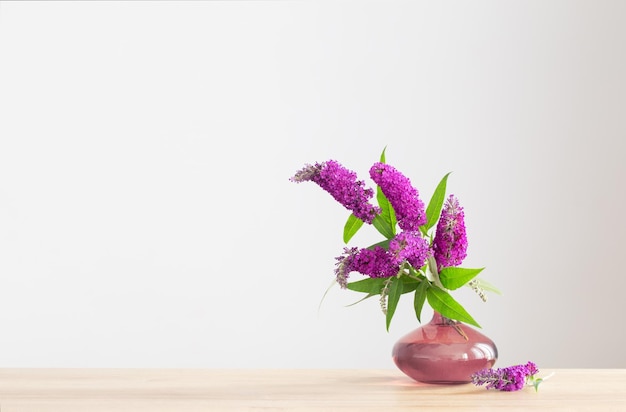 Summer lilac in glass vase on wooden shelf