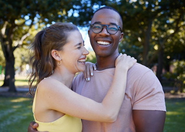 Summer love and laugh with an interracial couple hugging outdoor together in a park or garden Nature diversity and romance with a man and woman bonding while on a date outside in the countryside