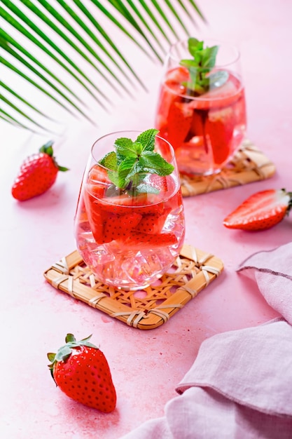 Summer mint and strawberry infused water on pink table top still life top view Summer fruity refreshing cocktail still life closeup