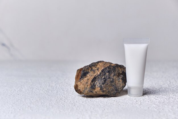 Summer mockup concept for product presentation cosmetic bottle tube and stone platform on white textured background