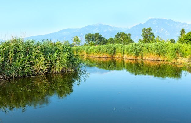 Summer morning misty mountain landscape with water surface in front  (Greece).