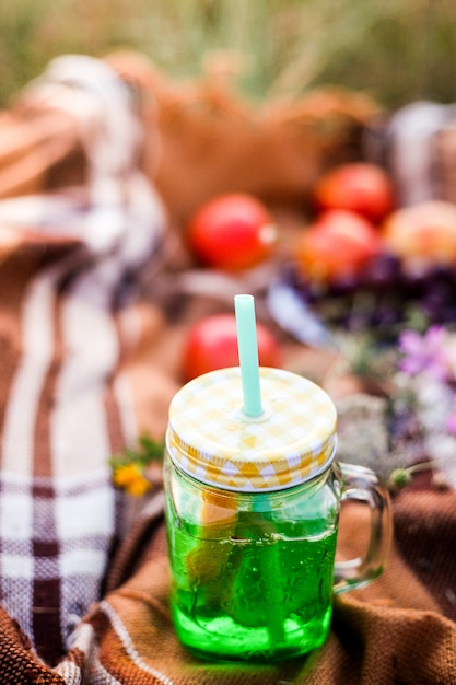 Summer picnic outdoors, summer drink jar with lemonade, plaid in the warm sunlight