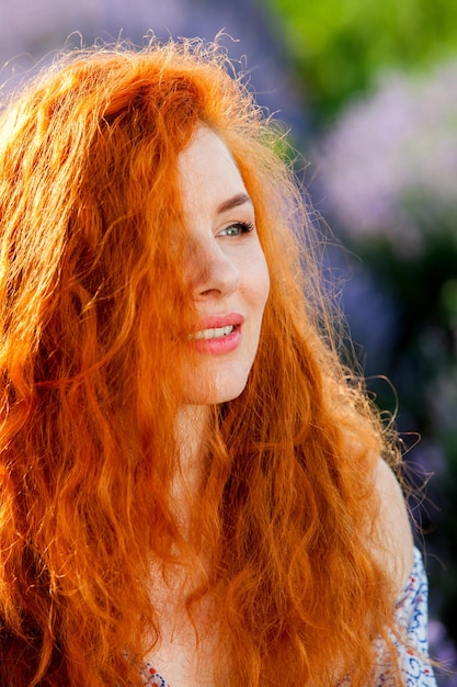 Photo summer portrait of a beautiful girl with long curly red hair woman with long hair