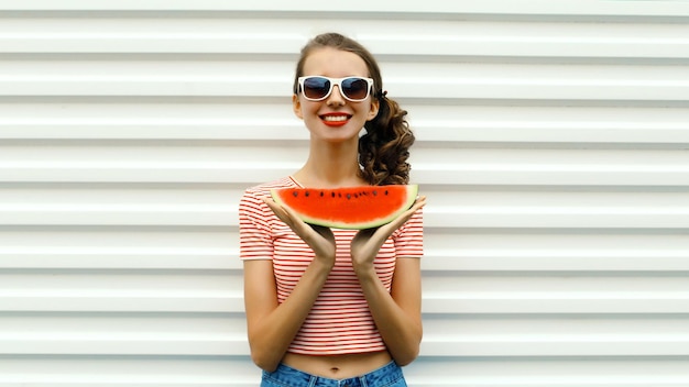 Photo summer portrait happy young woman eating fresh slice of watermelon in glasses on white background