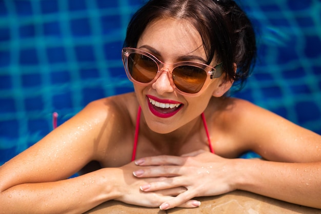 Summer positive portrsit of brunette woman in bikini having fun at swiming pool