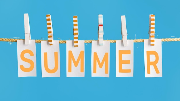 Summer poster with lettering summer inscription on white pieces of paper hanging on rope on blue