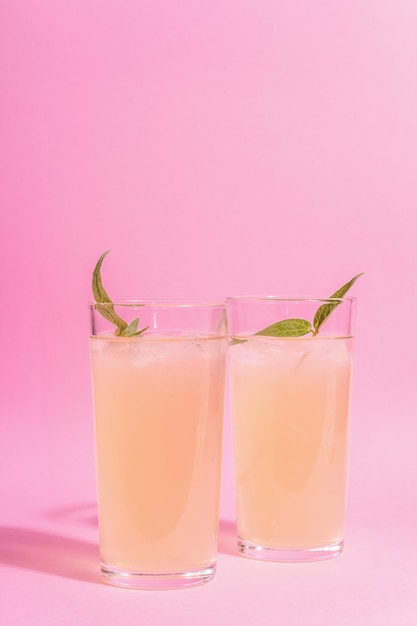 Summer refreshing cocktail. Cold sweet drink, modern hard light, dark shadow. Pastel pink background