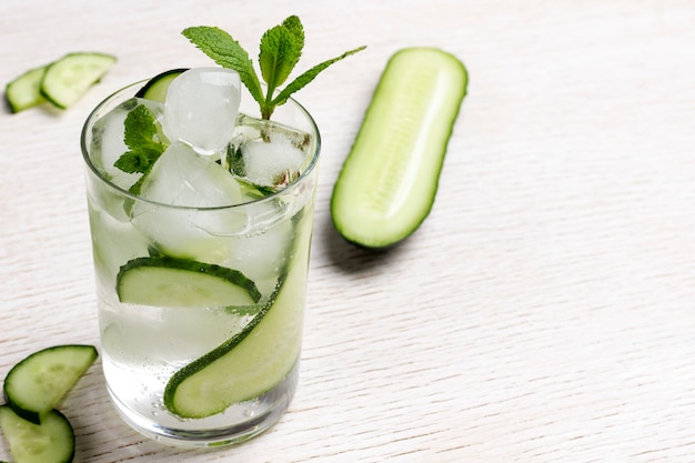 Summer refreshing drink with ice and slices of cucumber. Mint and chopped cucumber