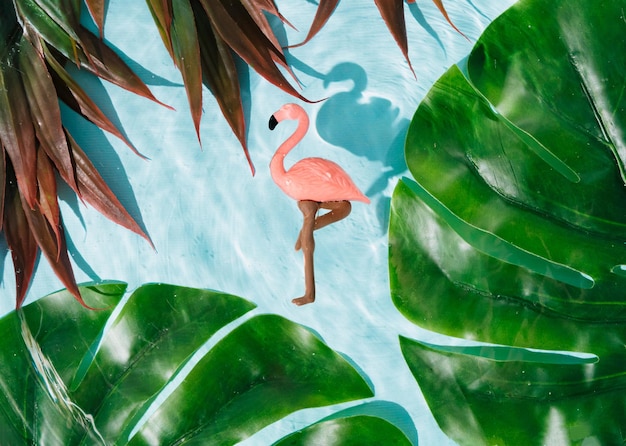 Summer and relax concept Pink flamingos on the clear bright blue wavy water with tropical leaves Summer relaxation and fun concept