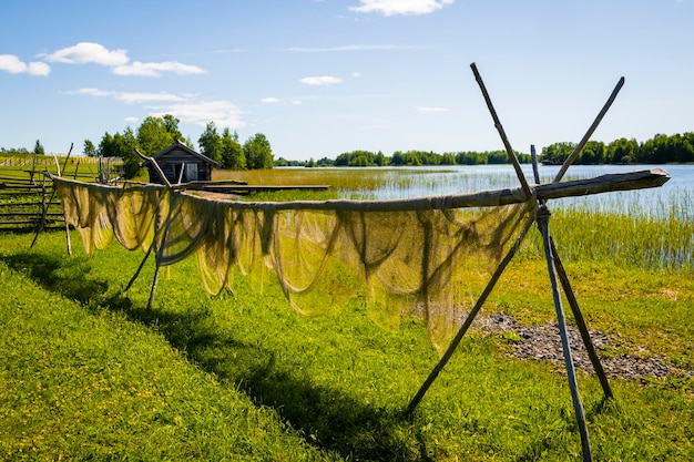 A summer rural landscape hanging drying fishing nets in the fresh air on the shore of the lake