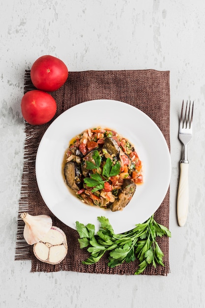 Summer salad of eggplant and tomato on a white plate