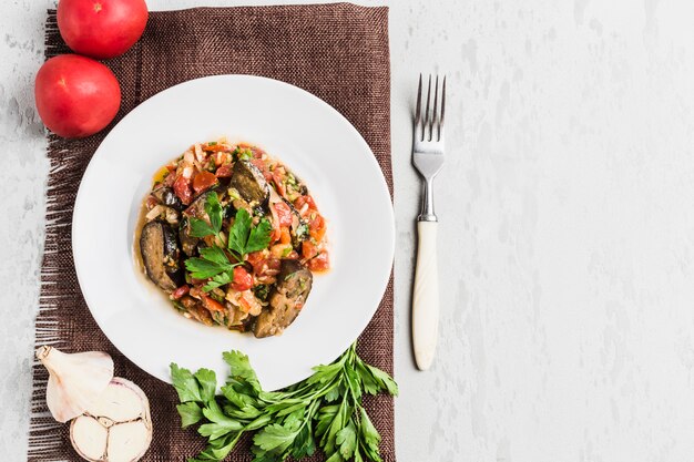 Summer salad of eggplant and tomato on a white plate