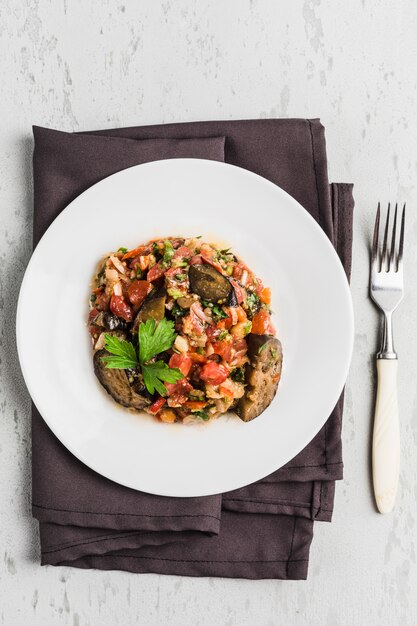 Summer salad of eggplant and tomato on a white plate